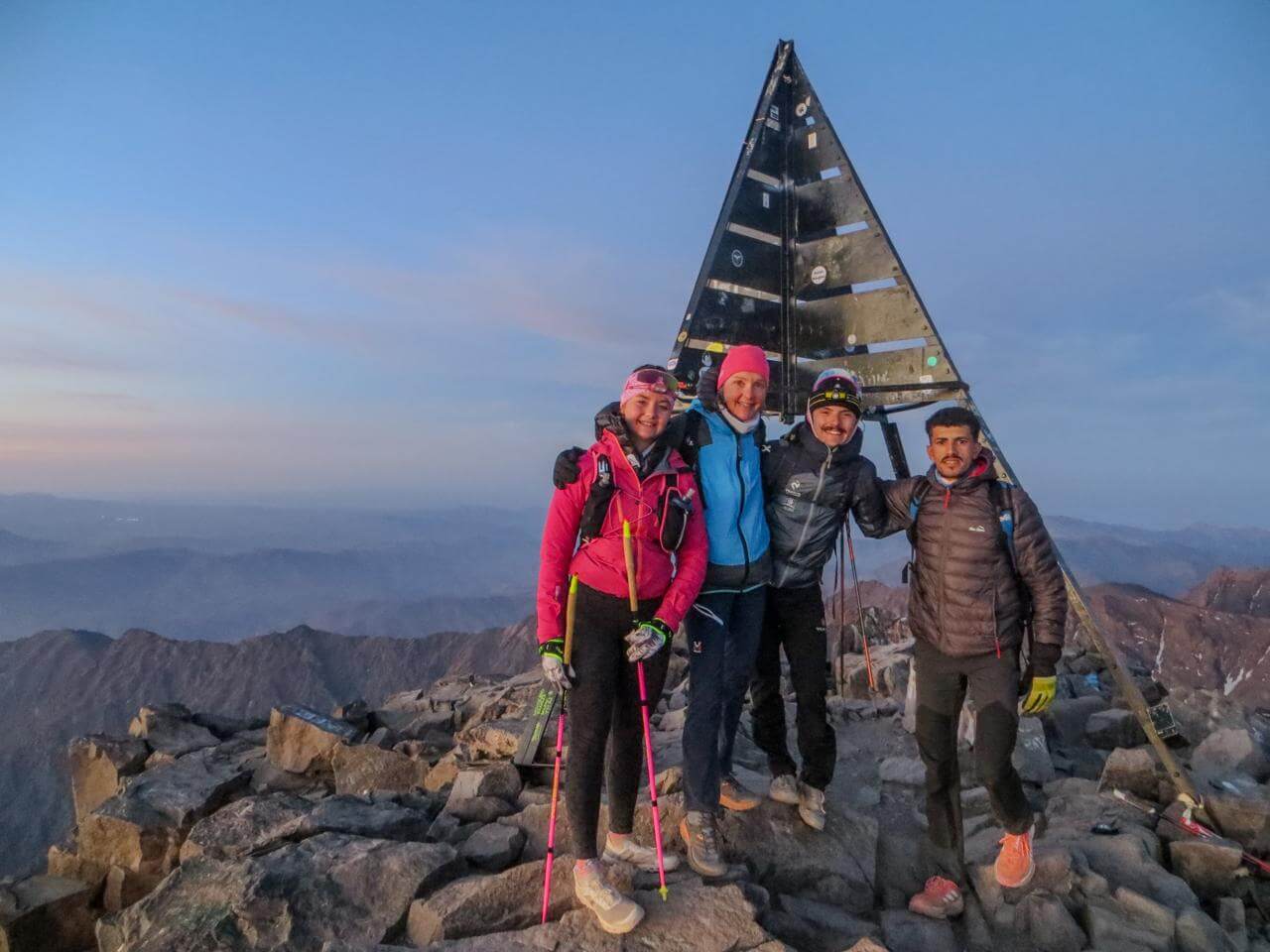 Trail runners celebrating together on the summit of Mount Toubkal at 4,167 metres in Morocco